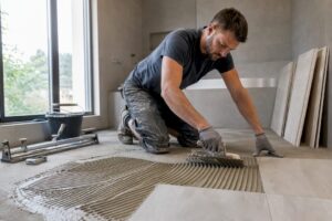 Mit geübten Händen wird der Fliesenkleber gleichmäßig mit einer Kelle aufgetragen.