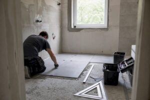 Hände verlegen große Badezimmerfliesen auf dem Boden