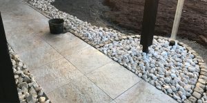 Außenbereich mit hellen Platten, weißen Kieseln und geschwungener Einfassung