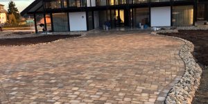 Großzügige gepflasterte Einfahrt mit geschwungener Linienführung vor modernem Gebäude