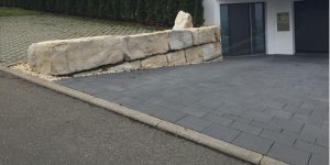 Dunkel gepflasterte Einfahrt mit großen Natursteinblöcken am Hauseingang