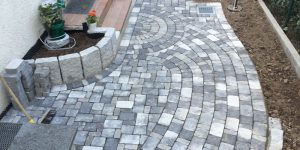 Geschwungener Pflasterweg in Grau- und Blautönen mit dekorativem Verlegemuster